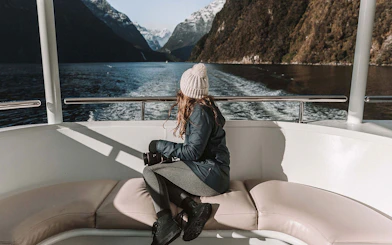 Lady on a boat viewing Milford Sound fjords in New Zealand.