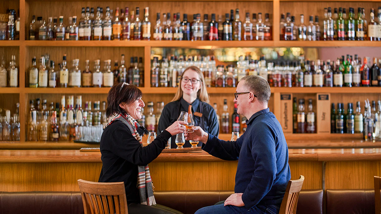 Couple toasting whisky glasses at a bar during The Gold Tour - Scotch Whisky Experience.