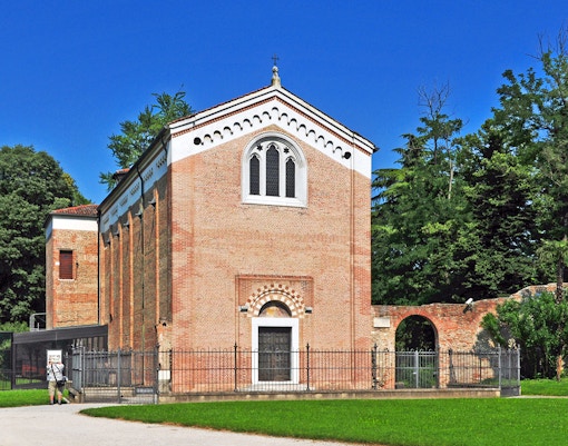 Giotto Scrovegni Chapel exterior in Padua surrounded by trees.