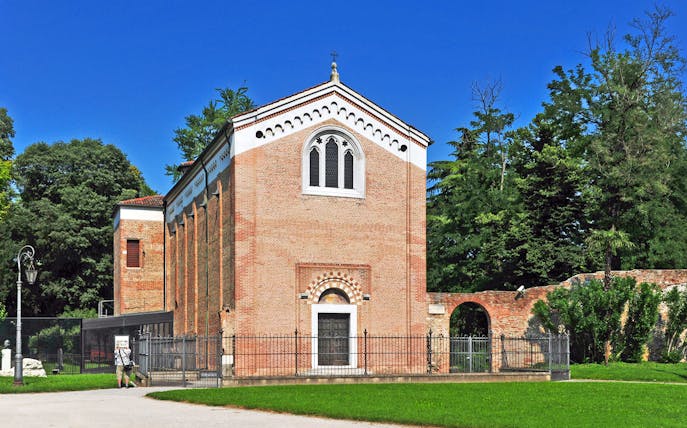 Giotto Scrovegni Chapel exterior in Padua surrounded by trees.