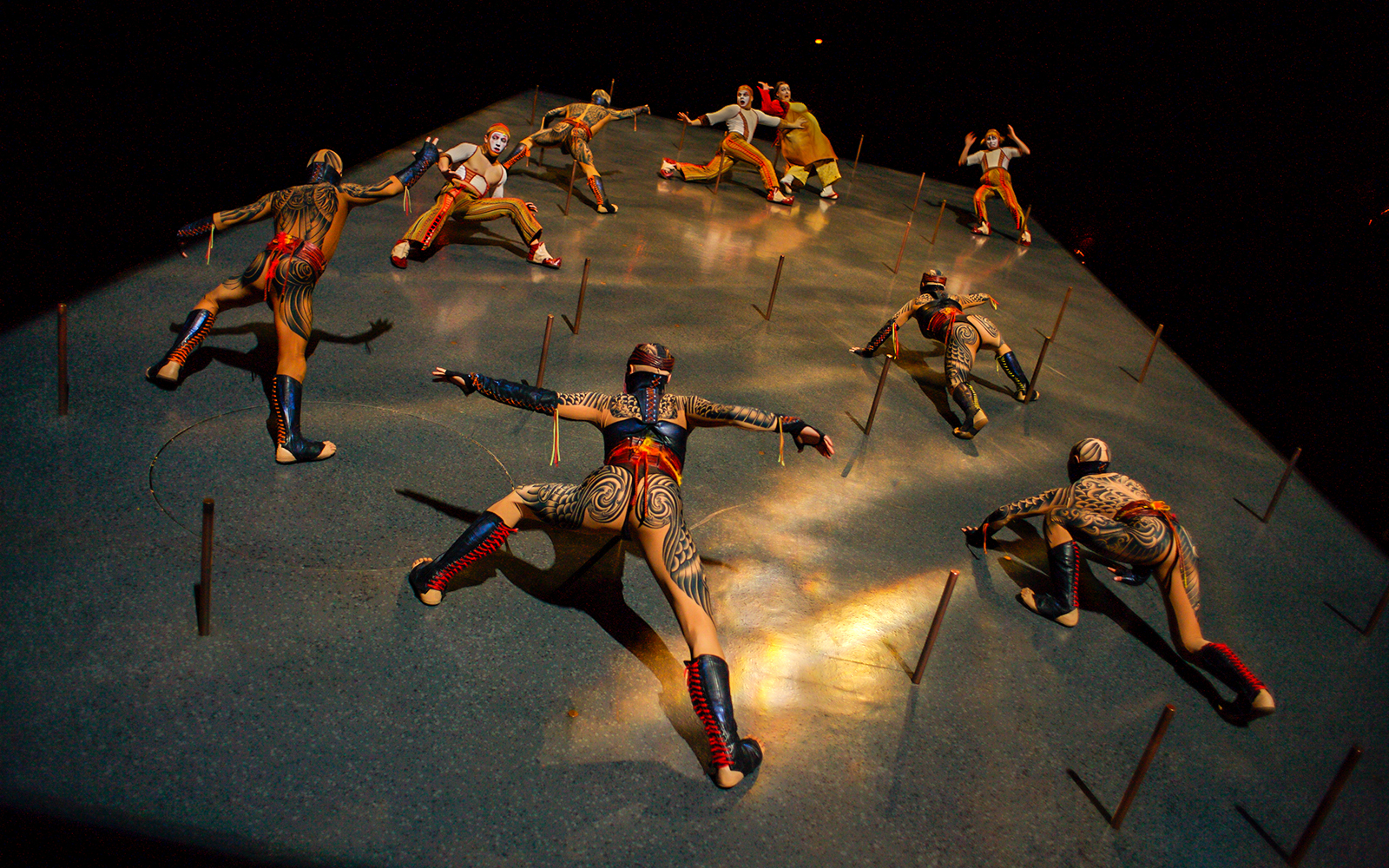 Performers in intricate costumes climbing a vertical stage in Cirque du Soleil KÀ show.