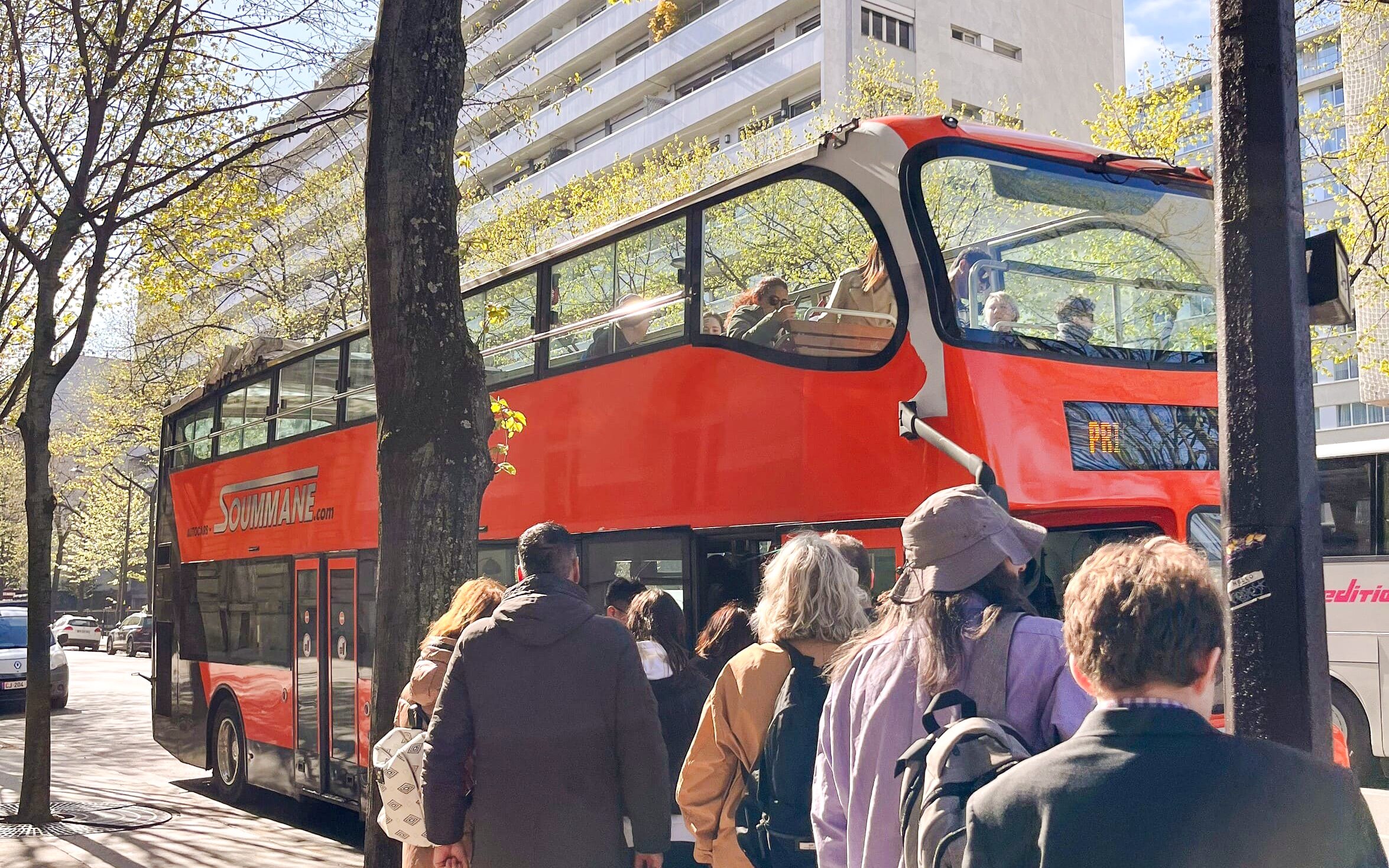 Tourists boarding a red double-decker bus for the Illumination Tour of Paris and Eiffel Tower.