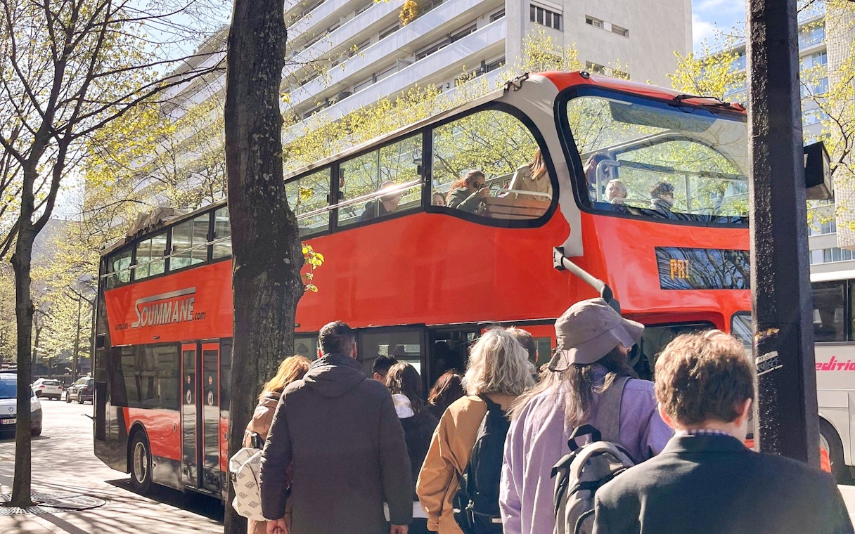 Tourists boarding a red double-decker bus for the Illumination Tour of Paris and Eiffel Tower.