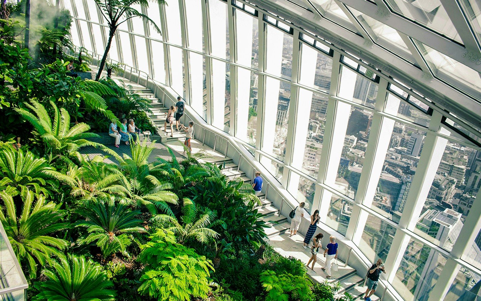 Visitors exploring lush greenery inside Sky Garden, London with city views.
