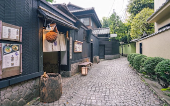Traditional Japanese street in Tokyo with wooden buildings and cobblestone path.