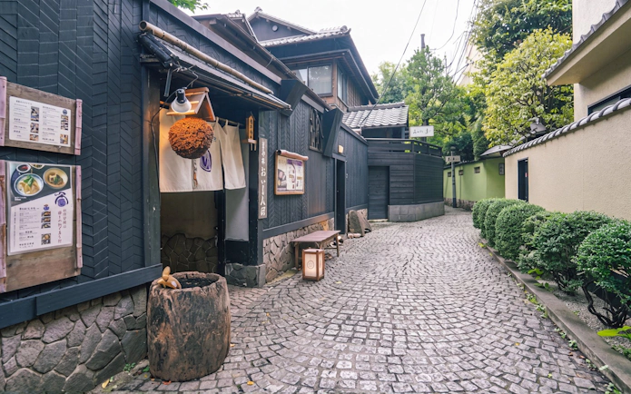 Traditional Japanese street in Tokyo with wooden buildings and cobblestone path.