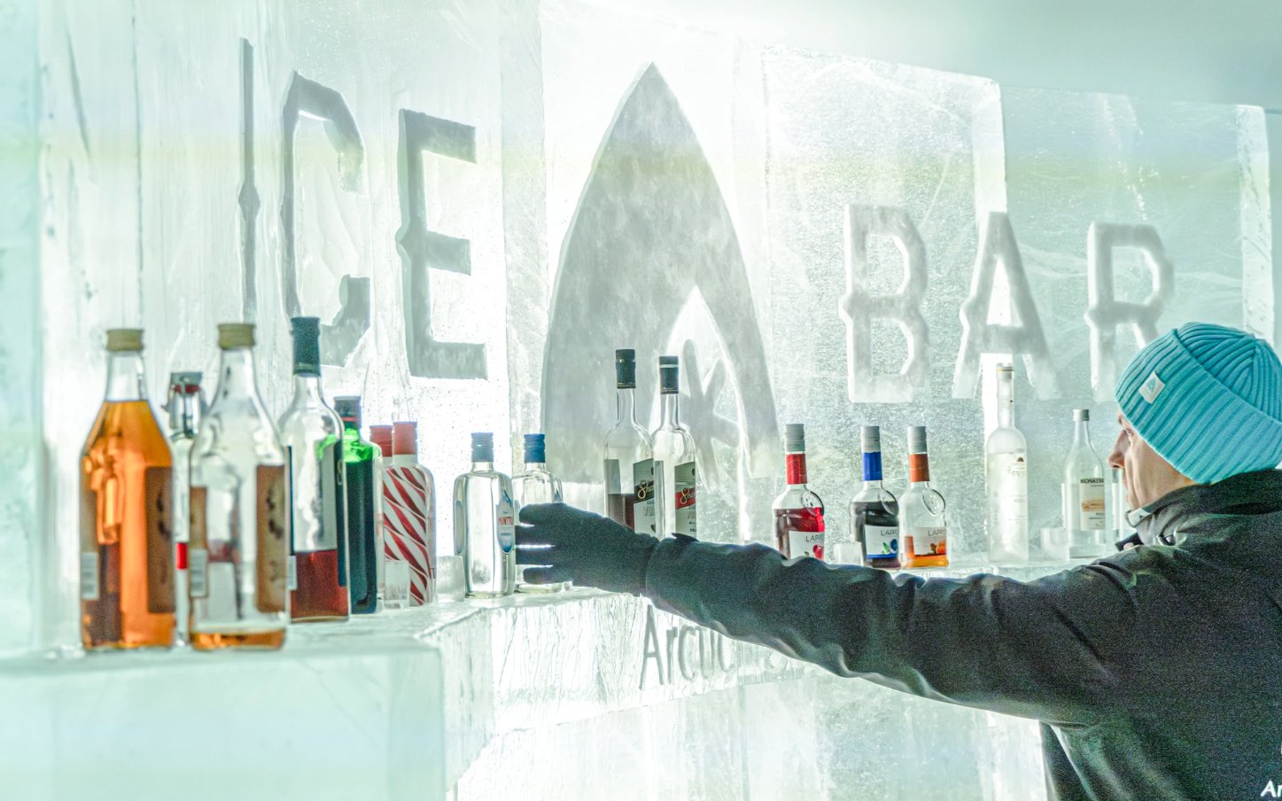 Guest reaching for a bottle at the ice bar inside Arctic SnowHotel.