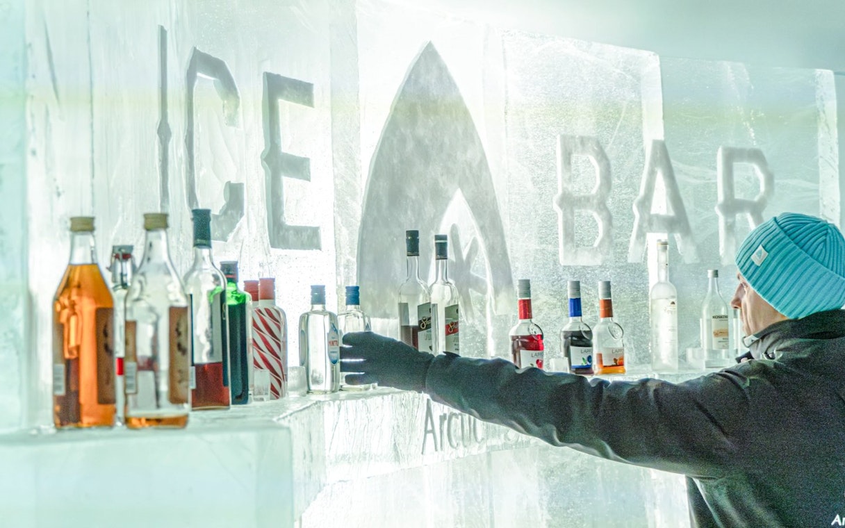 Guest reaching for a bottle at the ice bar inside Arctic SnowHotel.