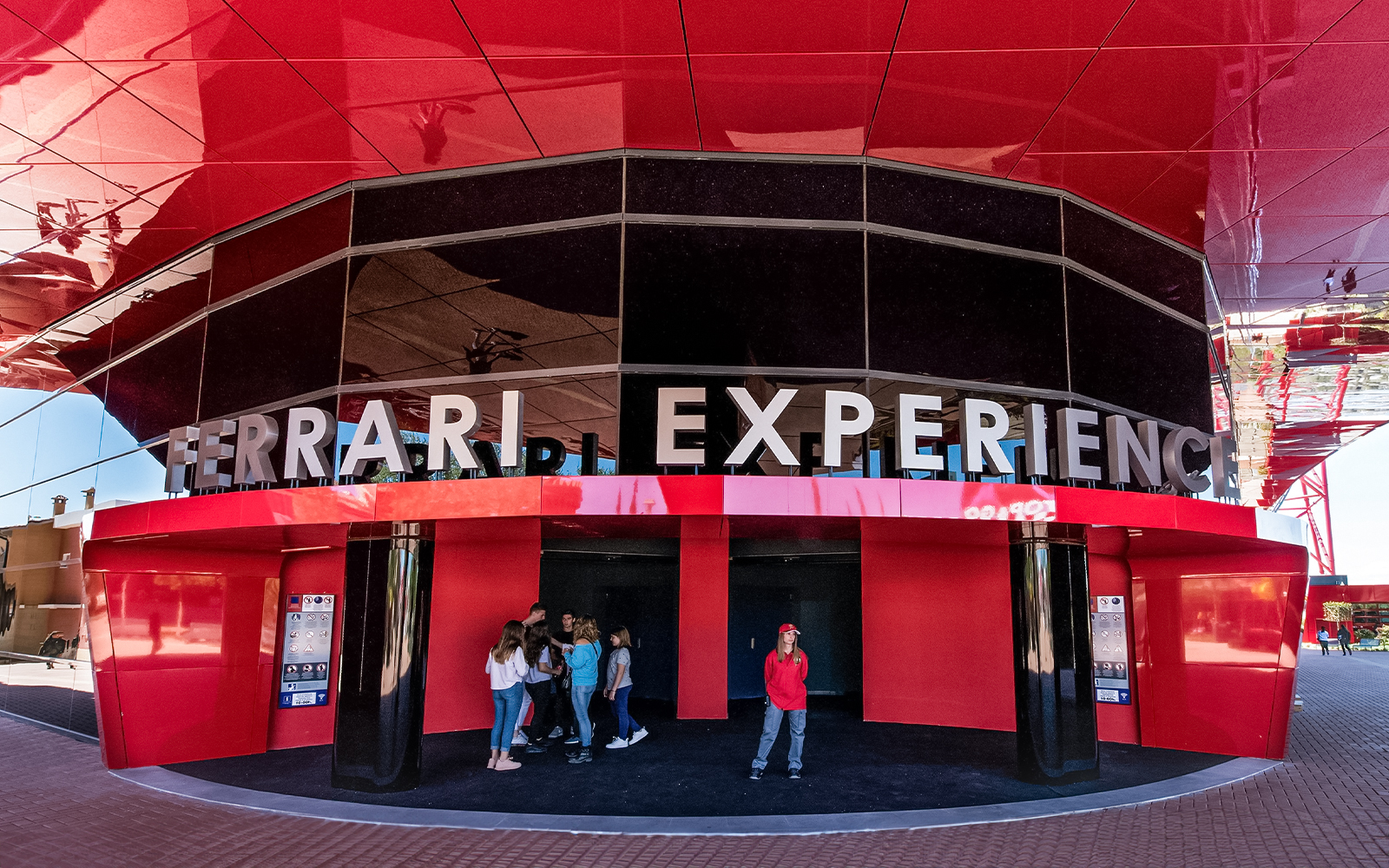 Ferrari Land entrance with visitors at the Ferrari Experience building.