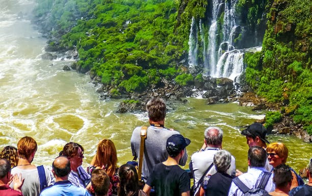 Visitors viewing Iguazu Falls from a platform in Brazil.
