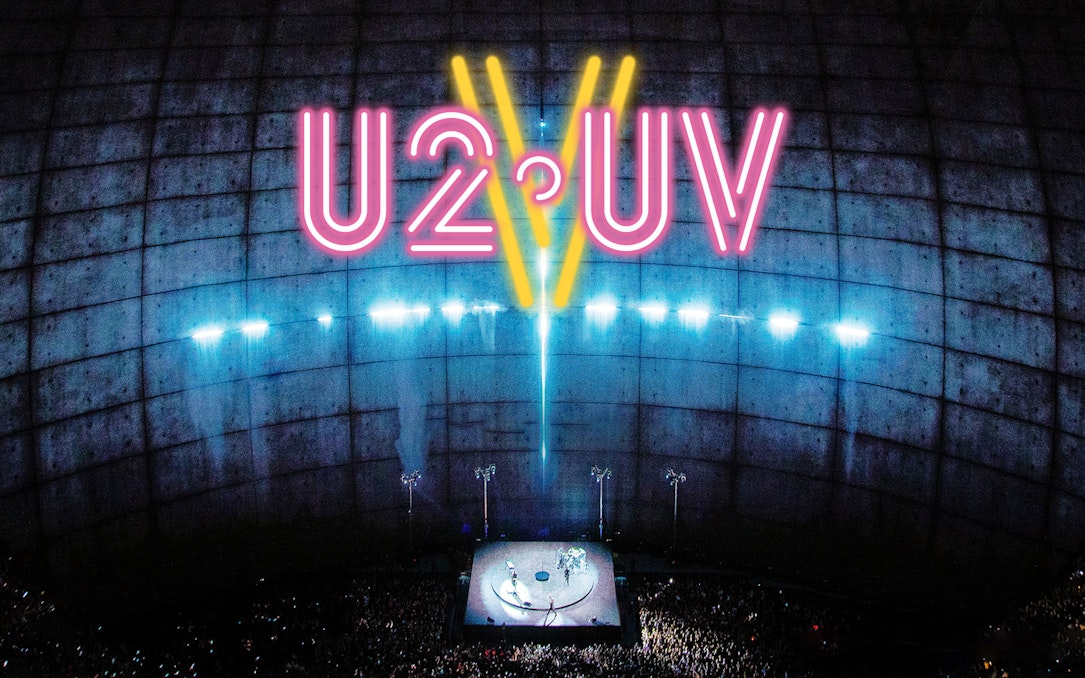 U2 concert at Sphere Las Vegas with neon lights and large audience.