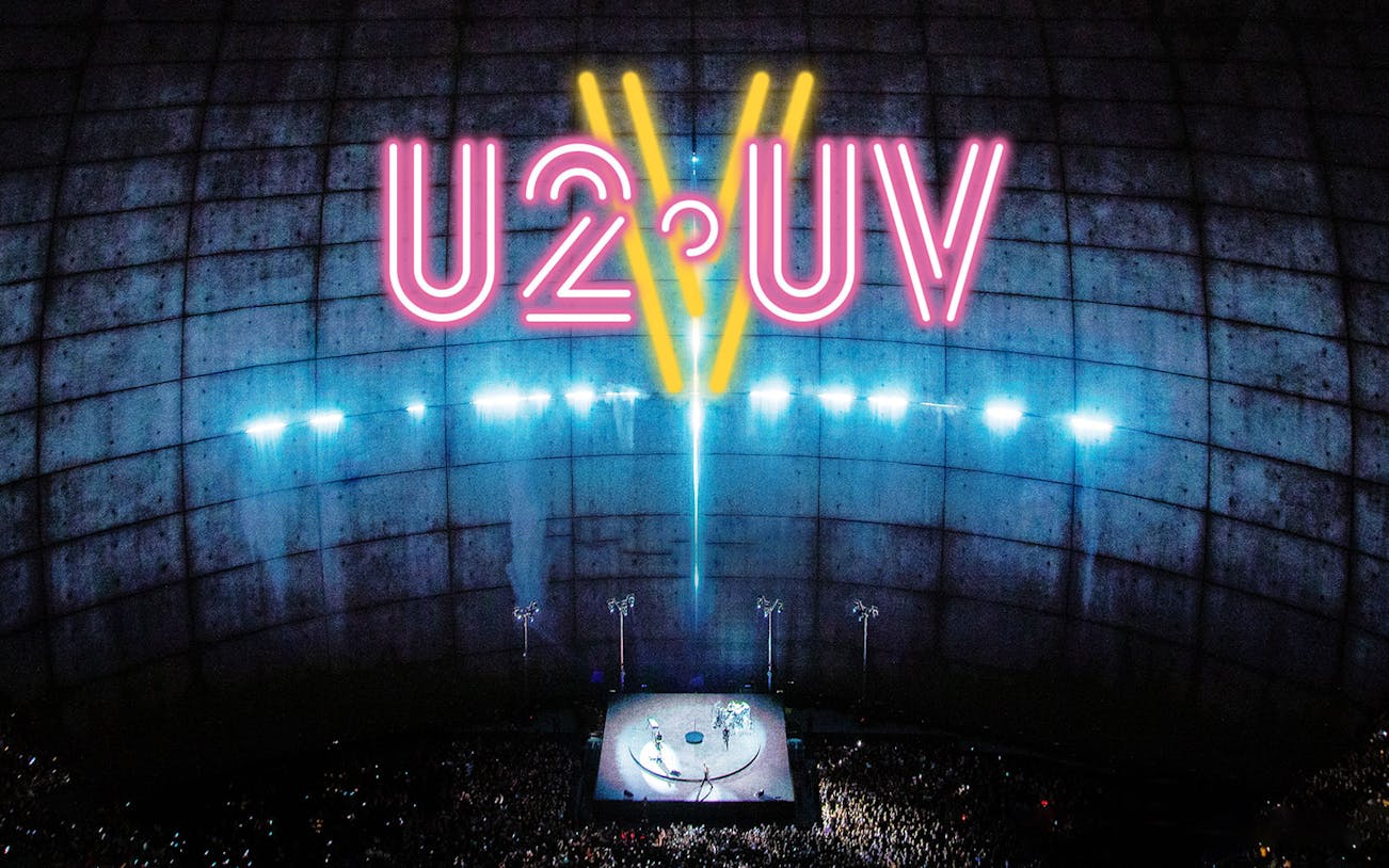 U2 concert at Sphere Las Vegas with neon lights and large audience.