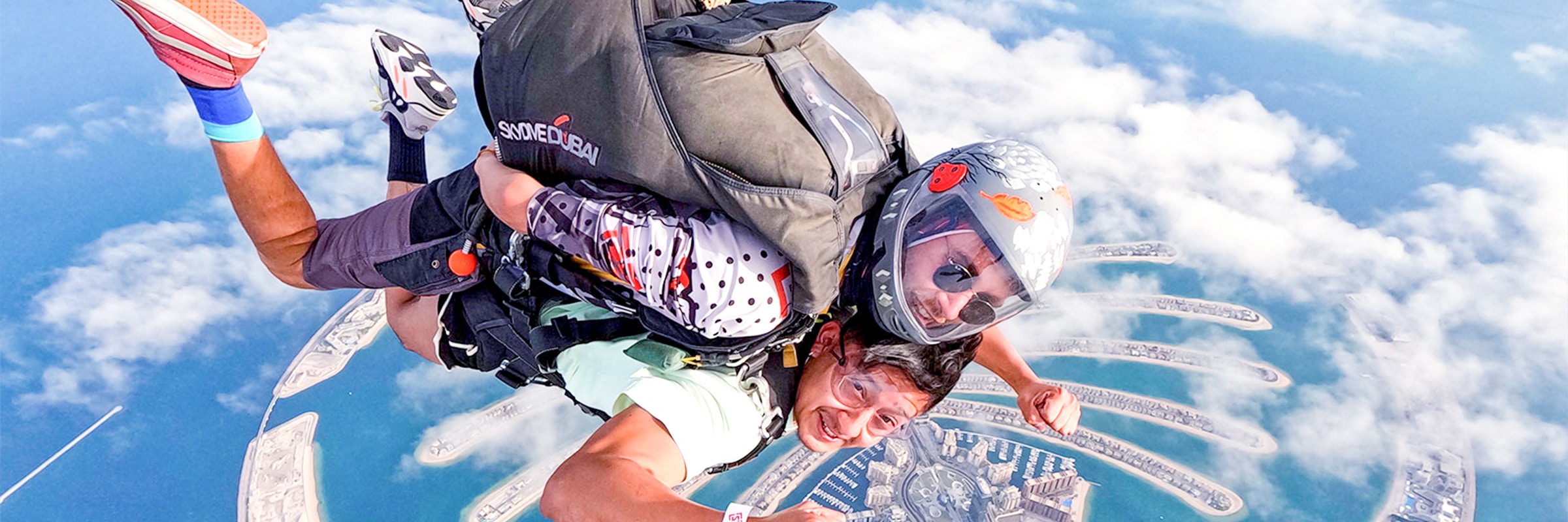 Skydiver descending over Dubai Marina with Palm Jumeirah in the background.