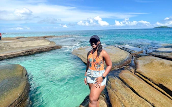 Woman standing on rocky shore with clear water, Archipiélago de las Perlas, Panama.