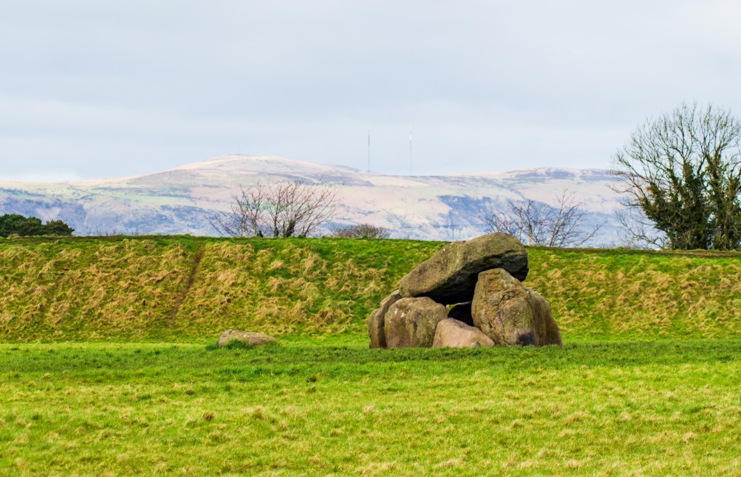 Neolithic dolmen at Giant's Ring, Belfast, surrounded by lush greenery.