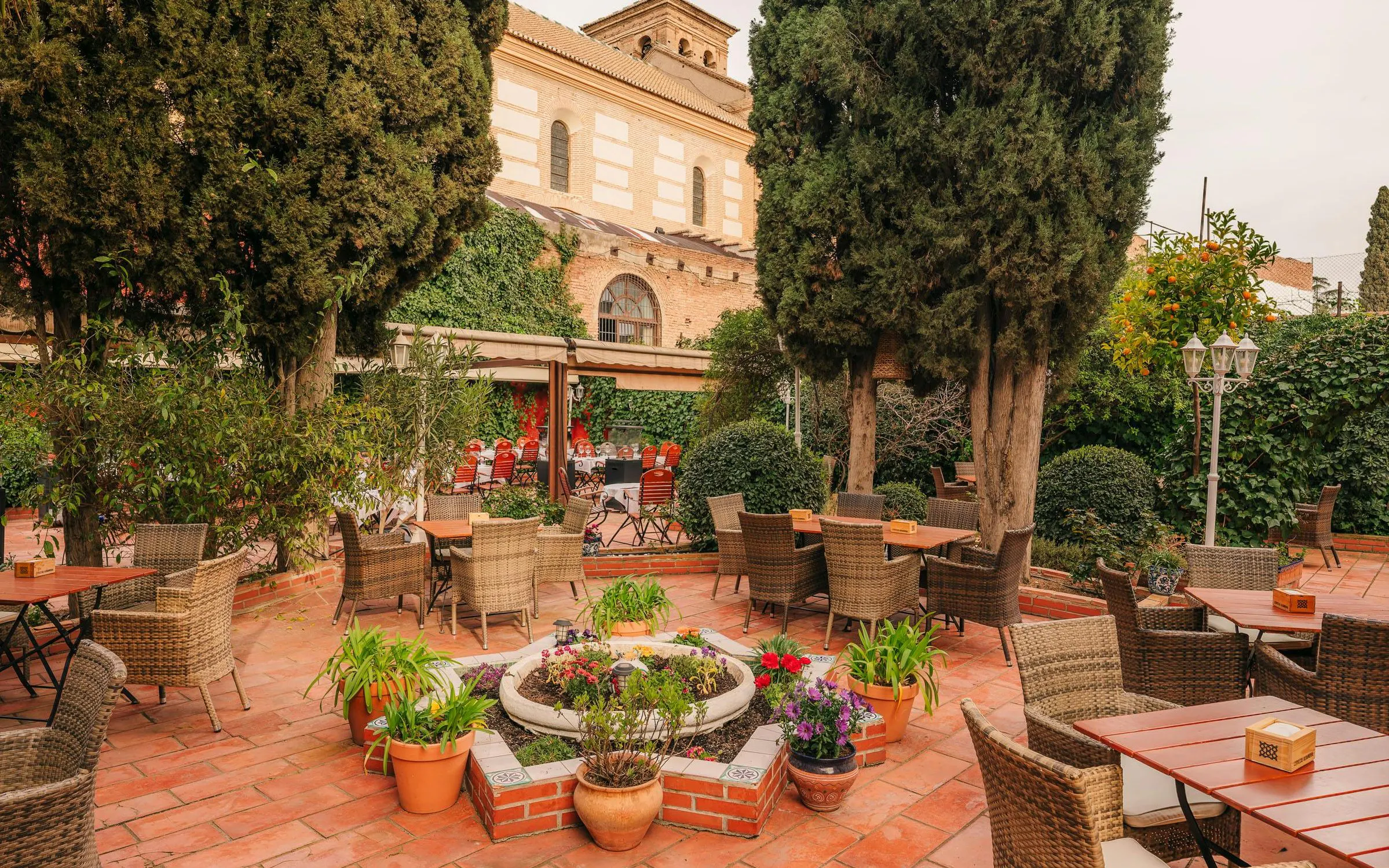 Outdoor seating area at Tablao Jardines de Zoraya, surrounded by lush greenery and potted plants.