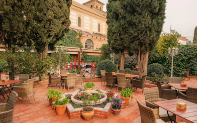 Outdoor seating area at Tablao Jardines de Zoraya, surrounded by lush greenery and potted plants.