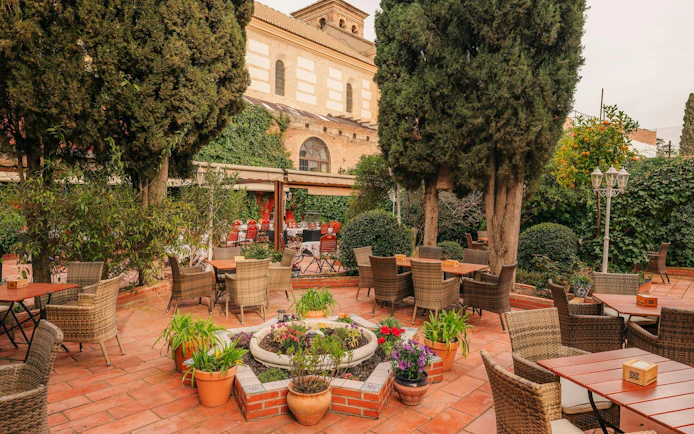 Outdoor seating area at Tablao Jardines de Zoraya, surrounded by lush greenery and potted plants.