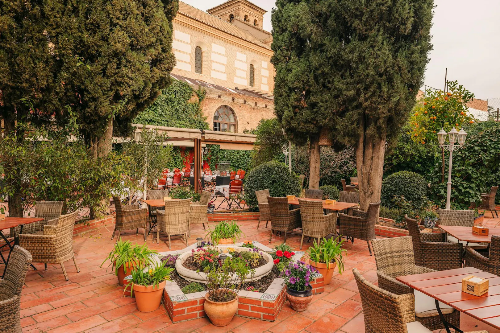 Outdoor seating area at Tablao Jardines de Zoraya, surrounded by lush greenery and potted plants.