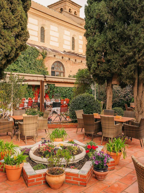 Outdoor seating area at Tablao Jardines de Zoraya, surrounded by lush greenery and potted plants.