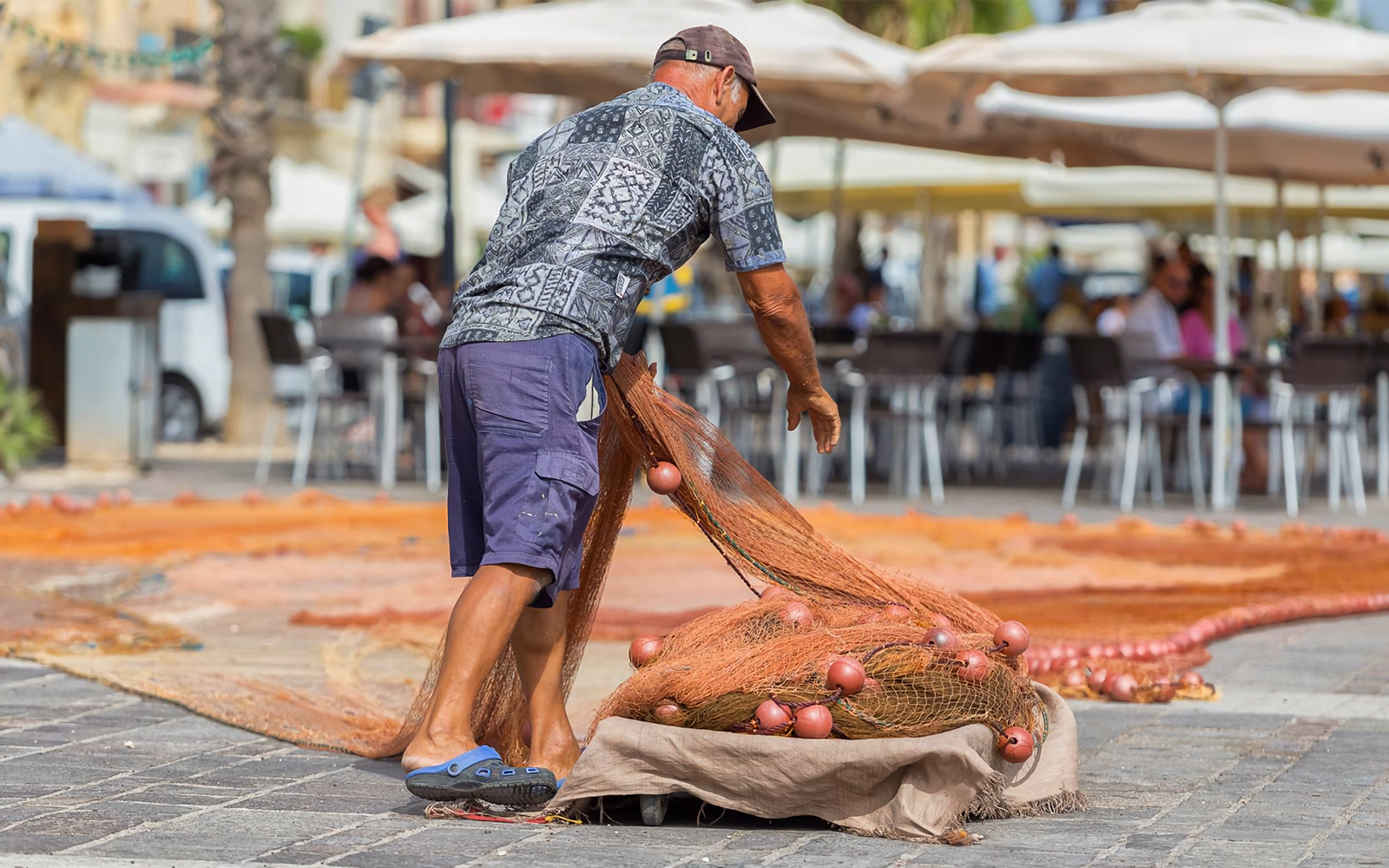 Fisherman handling nets at Marsaxlokk Fishing Village market, Malta.