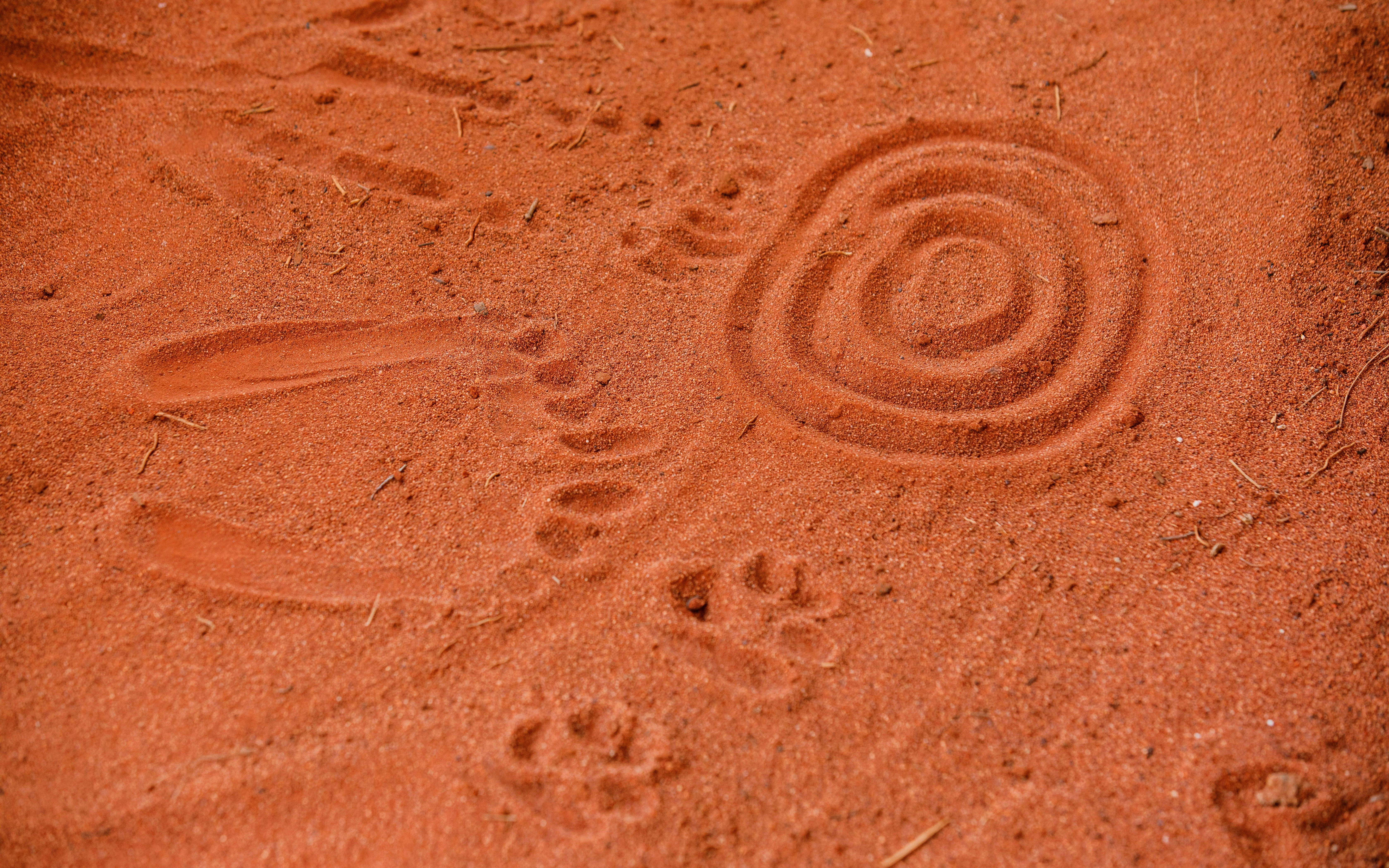 Aboriginal sand art and footprints at Uluru during sunrise tour.