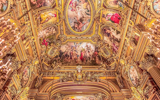 Ornate ceiling frescoes at Opera Garnier, Paris, featuring classical figures and gold detailing.