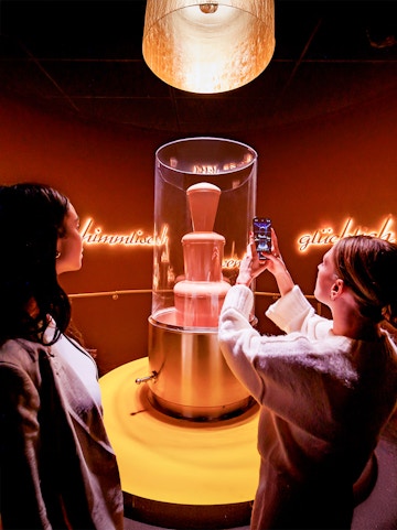 Tourists photographing chocolate fountain at Chocoversum, Hamburg.