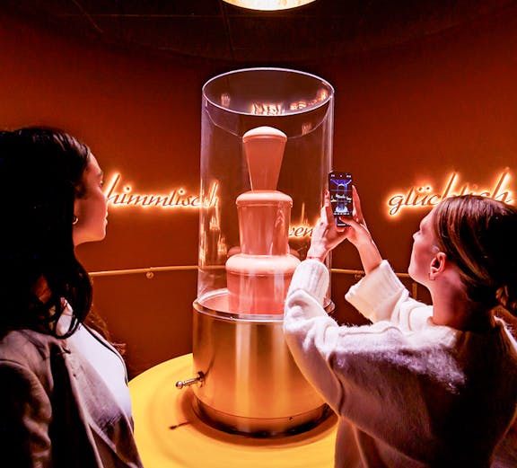 Tourists photographing chocolate fountain at Chocoversum, Hamburg.