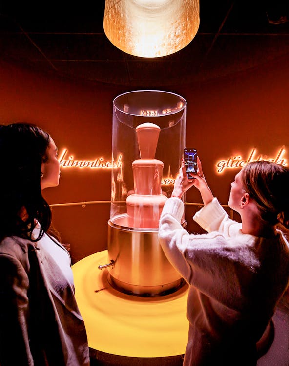 Tourists photographing chocolate fountain at Chocoversum, Hamburg.