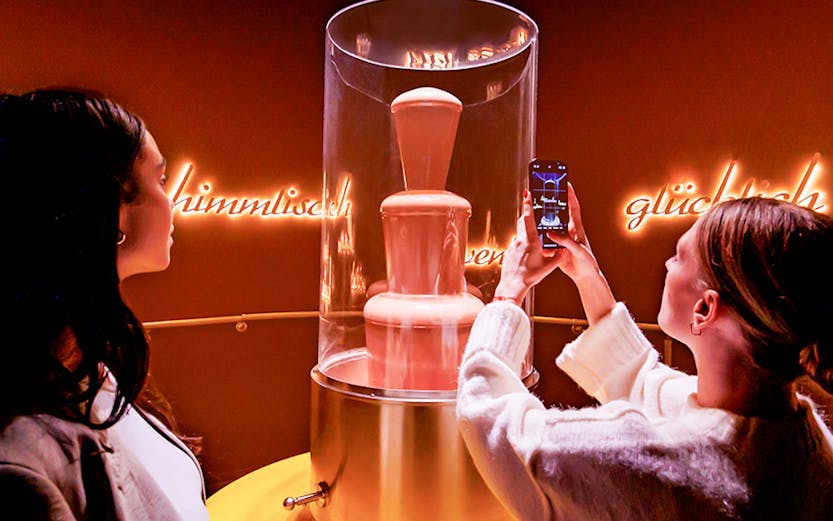 Tourists photographing chocolate fountain at Chocoversum, Hamburg.