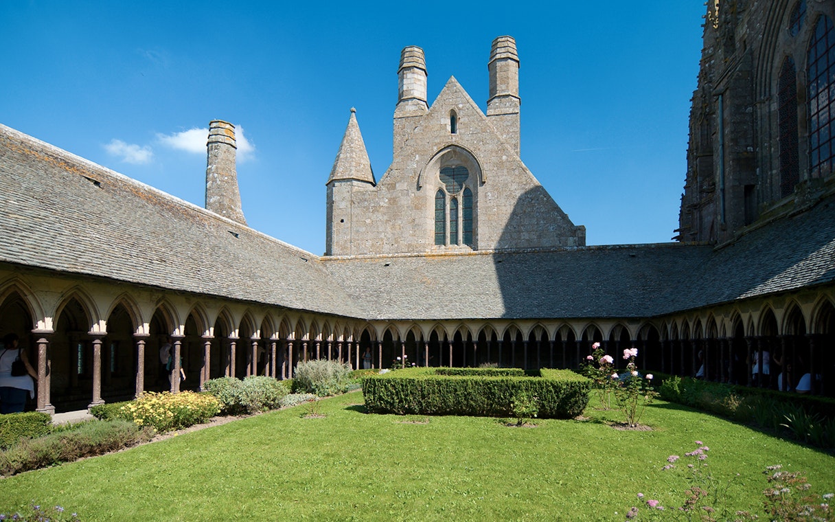 Cloister garden at Mont Saint Michel Abbey, France, under a clear blue sky.