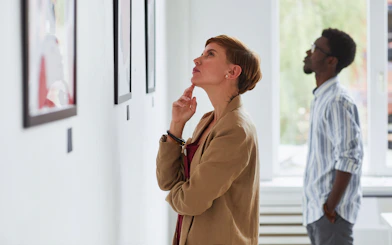 Young woman viewing paintings in a modern art gallery exhibition.