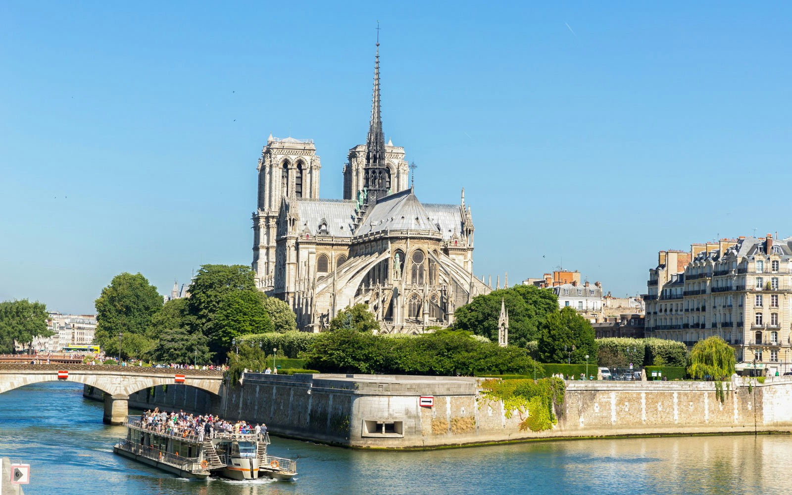 Seine River cruise ship near Notre Dame, Paris, with passengers enjoying champagne.