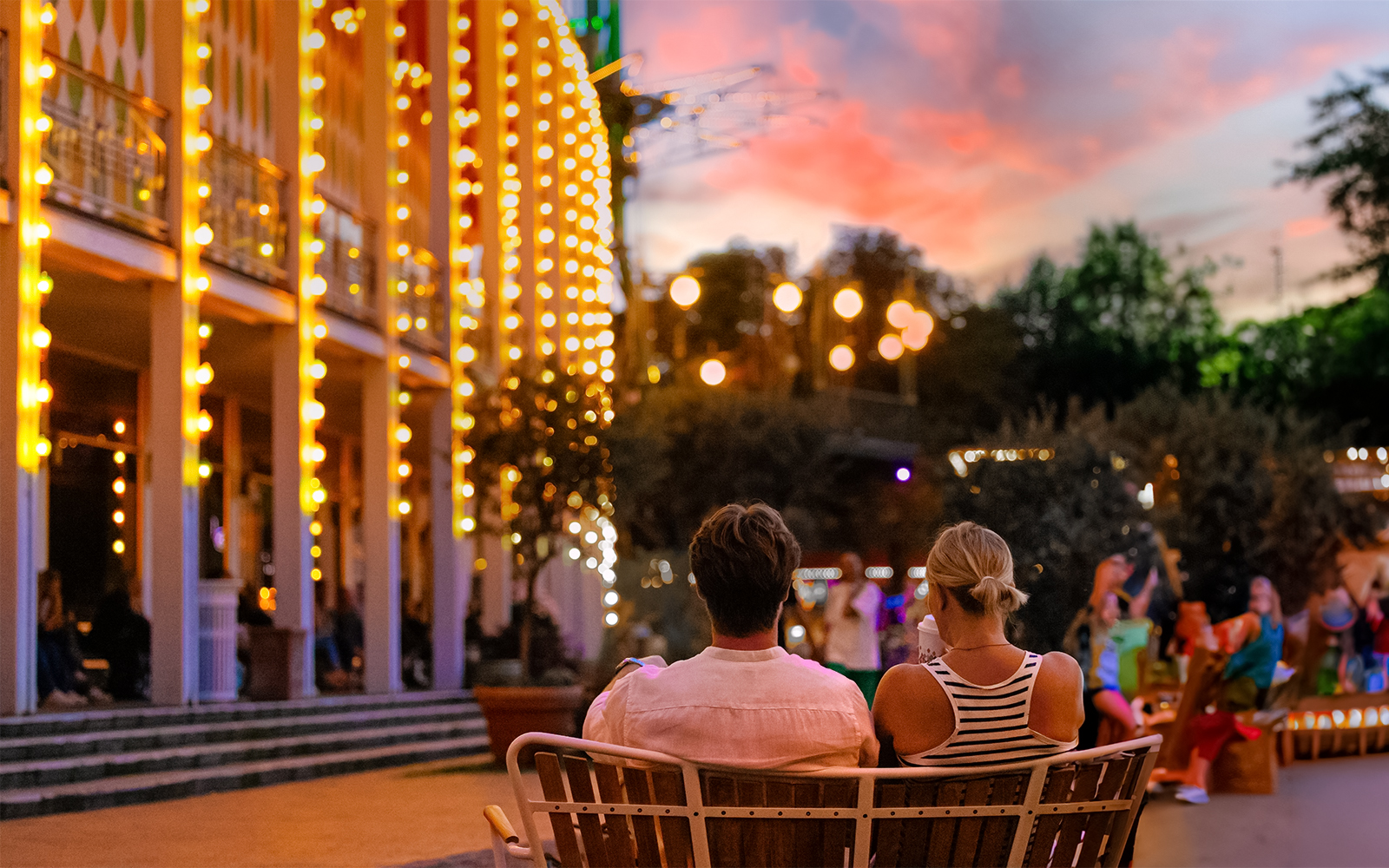 Couple sitting on a bench at Tivoli Gardens, Copenhagen during evening lights.