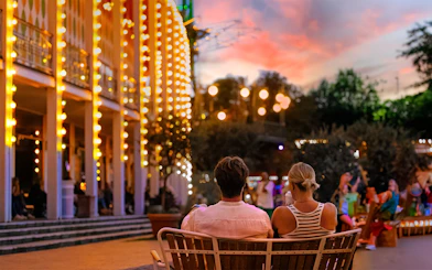 Couple sitting on a bench at Tivoli Gardens, Copenhagen during evening lights.