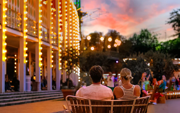 Couple sitting on a bench at Tivoli Gardens, Copenhagen during evening lights.