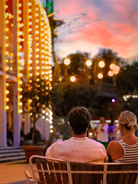 Couple sitting on a bench at Tivoli Gardens, Copenhagen during evening lights.