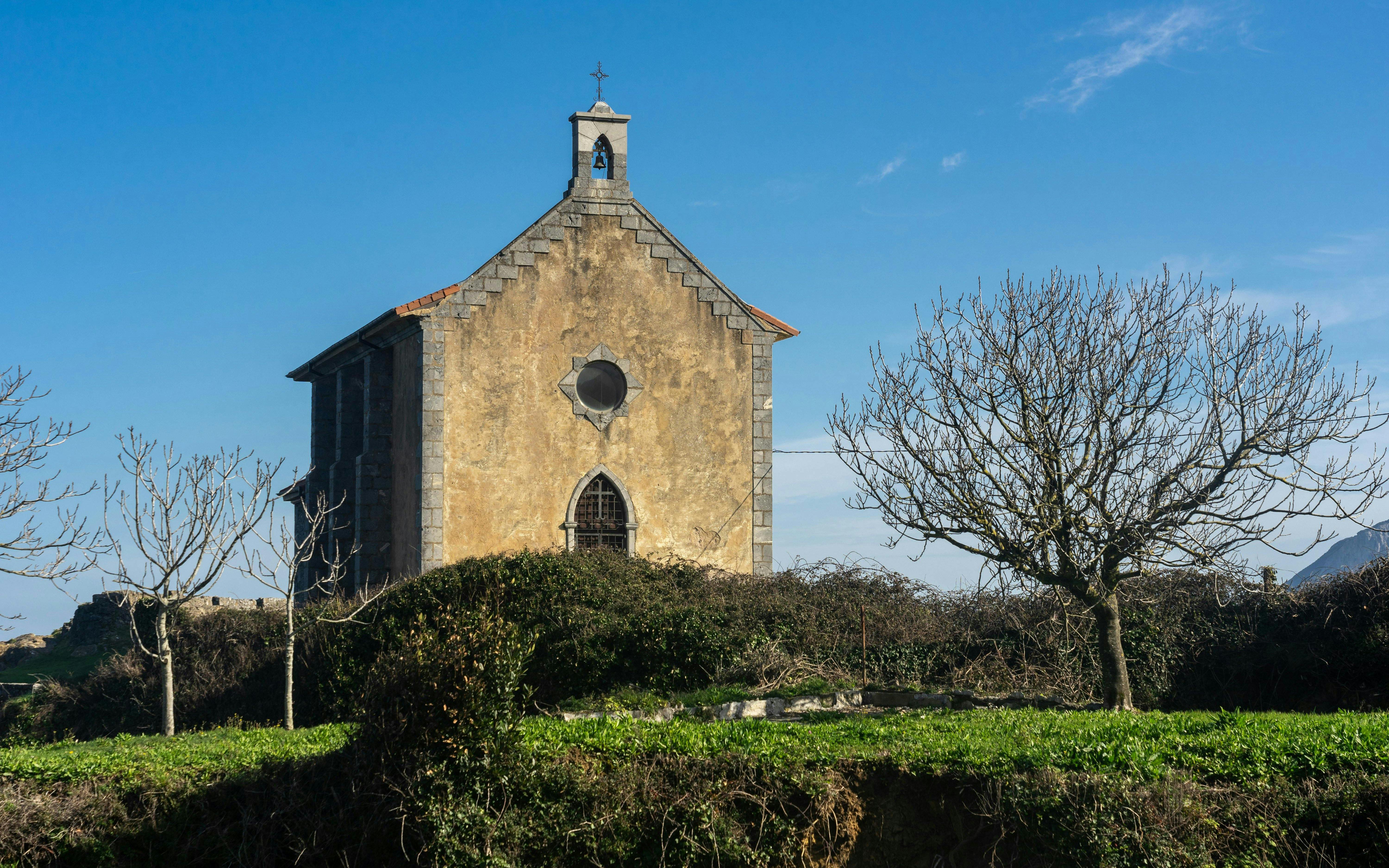 Santa Catalina hermitage surrounded by trees in Mundaka, Vizcaya, Spain.