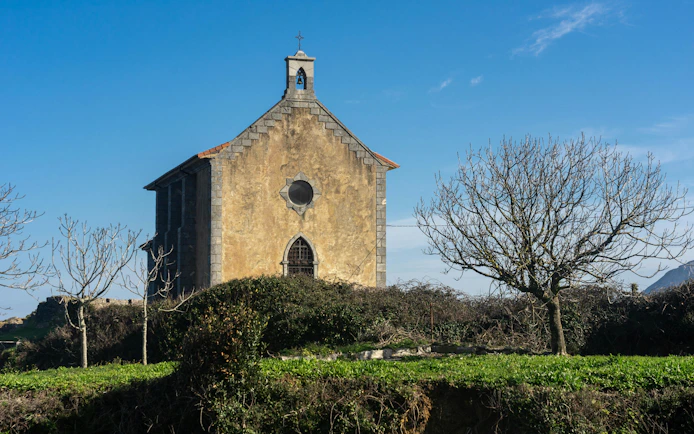 Santa Catalina hermitage surrounded by trees in Mundaka, Vizcaya, Spain.