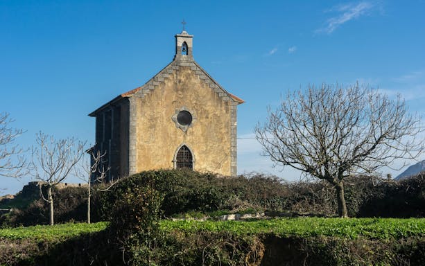 Santa Catalina hermitage surrounded by trees in Mundaka, Vizcaya, Spain.