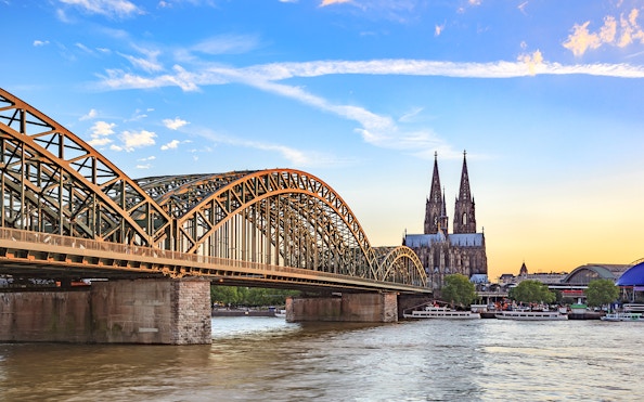 Hohenzollern Bridge over Rhine River with Cologne Cathedral at sunset.