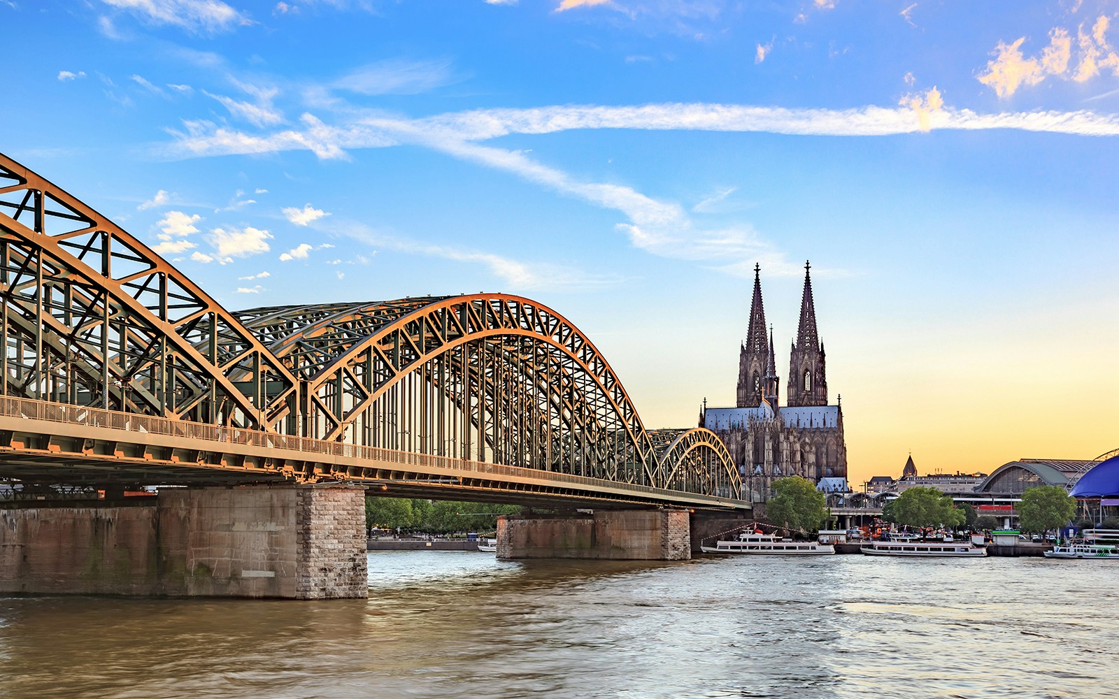 Hohenzollern Bridge over Rhine River with Cologne Cathedral at sunset.
