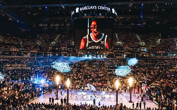 Barclays Center packed for Brooklyn Nets game with large screen and cheering crowd.