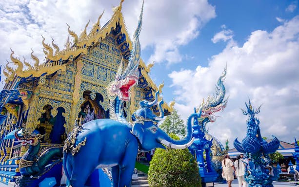 Blue Temple (Wat Rong Sua Ten) with intricate blue and gold designs and mythical sculptures in Chiang Rai, Thailand.
