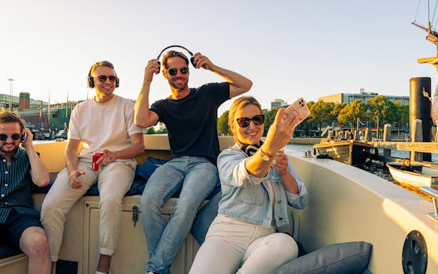 Group enjoying a party cruise in Amsterdam with headphones and drinks.