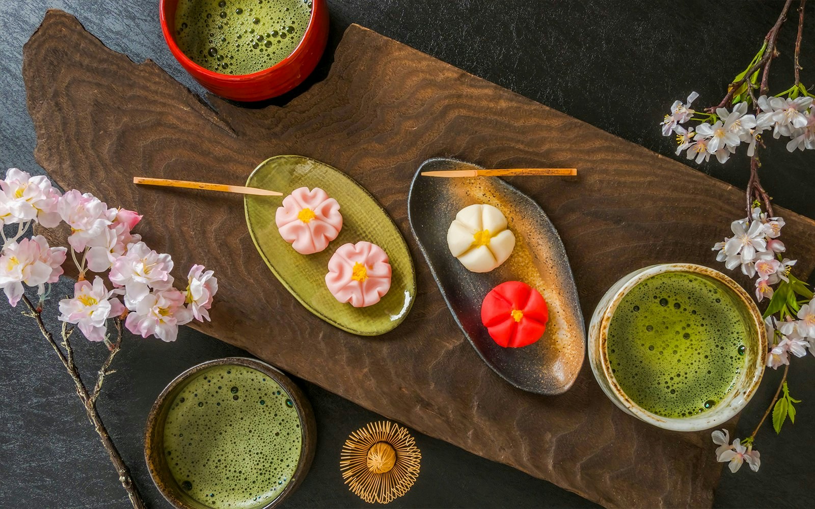 Matcha tea with traditional Japanese wagashi sweets and cherry blossoms.