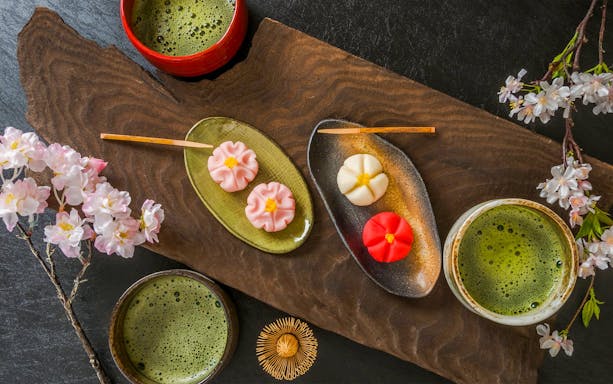 Matcha tea with traditional Japanese wagashi sweets and cherry blossoms.