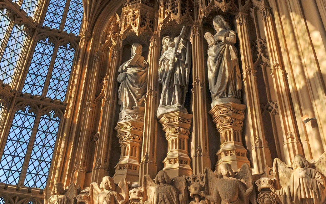 Statues inside Westminster Abbey, London, with intricate carvings and stained glass windows.