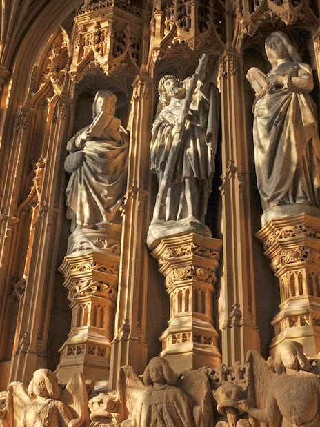 Statues inside Westminster Abbey, London, with intricate carvings and stained glass windows.